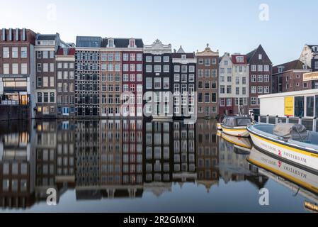 Typische Amsterdamer Häuser mit Reflexionen im Damrak-Kanal, Amsterdam, Nordholland, Niederlande Stockfoto