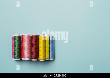 Ein Bündel farbiger Fäden auf einer glatten blauen Oberfläche Stockfoto