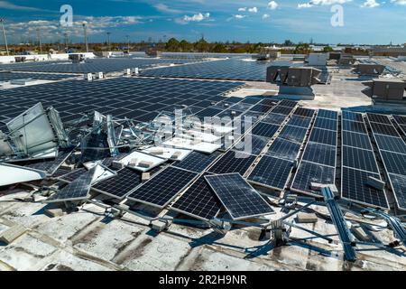 Draufsicht der durch den Hurrikan Ian zerstörten Photovoltaik-Solarpaneele, die auf dem Dach des Industriebaues zur Erzeugung von ökologischem Strom montiert sind Stockfoto