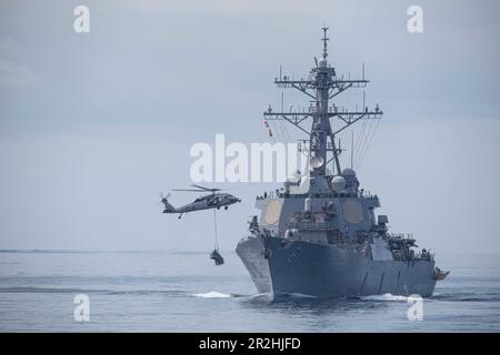 230518-N-LK647-1341 ATLANTISCHER OZEAN (18. Mai 2023) ein MH-60s Seahawk-Hubschrauber, der den „Tridents“ des Helicopter Sea Combat Squadron 9 (HSC 9) zugeteilt ist, führt eine vertikale Wiederauffüllung mit dem Trockenfrachtschiff der Lewis- und Clark-Klasse USNS Medgar Evers (T-AKE-13) und dem Arleigh Burke-Klasse-geführten Ramage-Zerstörer (DDG 61) durch. 18. Mai 2023. Normandy ist Teil der Gerald R. Ford Carrier Strike Group und befindet sich in einem geplanten Einsatz in den USA Marinestreitkräfte Europa Einsatzgebiet, angestellt von den USA Sechste Flotte, die die Interessen der USA, Verbündeten und Partner verteidigt. (USA Navy-Foto von Mass Communi Stockfoto