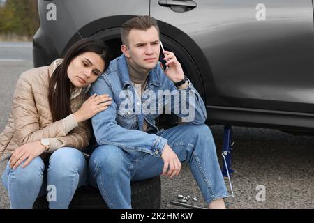 Ein junger Mann ruft beim Autoservice an. Reifenpanne Stockfoto
