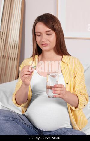 Eine schöne schwangere Frau, die zu Hause Pillen nimmt Stockfoto