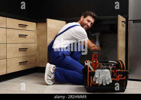 Professioneller Klempner in gleichmäßigem Spülbecken im Innenbereich Stockfoto