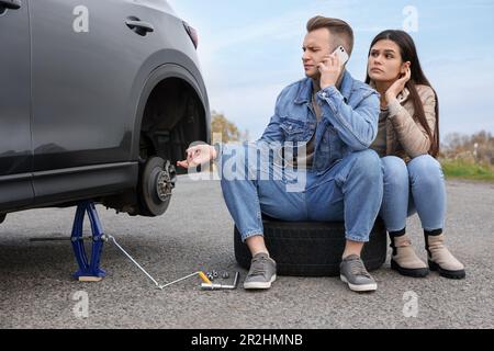 Ein junger Mann ruft beim Autoservice an. Reifenpanne Stockfoto