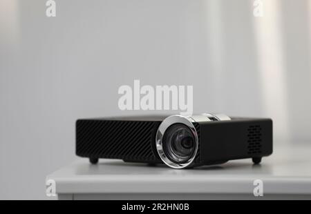 Moderner Videoprojektor auf weißem Tisch im Innenbereich Stockfoto