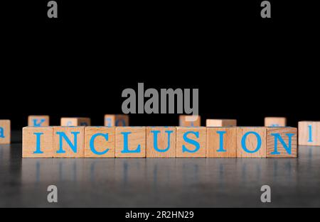 Holzwürfel mit Wort „Inclusion“ auf dunkelgrauem Tisch vor schwarzem Hintergrund. Platz für Text Stockfoto
