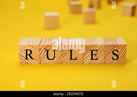 Wortregeln aus Holzwürfeln mit Buchstaben auf gelbem Hintergrund Stockfoto