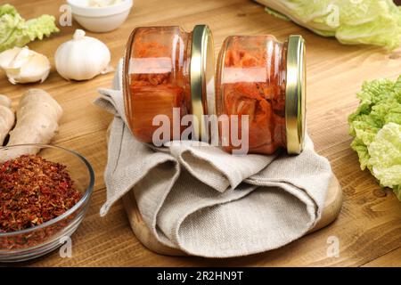 Köstlicher Kimchi mit Chinakohl und Zutaten auf Holztisch, Nahaufnahme Stockfoto