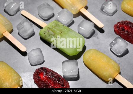 Leckere Knallbonbons und Eiswürfel auf dem grauen Tisch. Obst-Eis-Eis-Eis Stockfoto