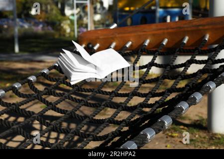 Komfortable NetzHängematte mit offenem Buch im Freien an sonnigen Tagen Stockfoto