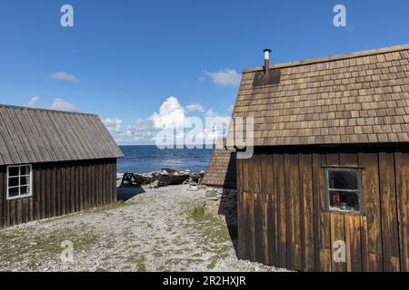 Blick zwischen 2 Fischerhütten auf einem alten kleinen Fischerboot am Kieselstrand, Faroe, Gotland, Schweden. Stockfoto