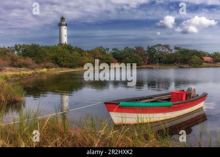 Kleines Fischerboot liegt am Ufer. Leuchtturm im Hintergrund. Boot und Turm werden reflektiert. Öland Norra Udde, Öland, langer Erik, Schweden. Stockfoto