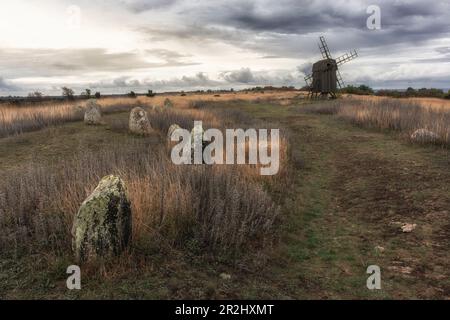 Stellen Sie Windmühlen und Steine auf Öland auf. Wolkiger Himmel. Pfad im Vordergrund. Oland, Schweden. Stockfoto