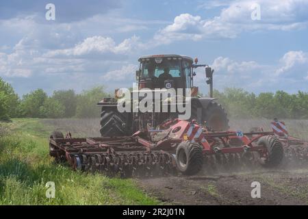 19. Mai 2023, Region Kherson, Ukraine: Das vor kurzem entminte Feld wird nach der Befreiung von der russischen Invasion für die Anpflanzung auf dem Bauernhof Pershe Travnia im Dorf Velyka Oleksandrivka in der Region Kherson gepflügt. Der Betrieb erzeugte Getreide (Weizen, Gerste, Sonnenblumen), Fleisch (Schweinefleisch) und andere Erzeugnisse; Mit 100 Beschäftigten und mehr als 3.000 Hektar Ackerfläche, mehr als 1200 Schweinen. Der Betrieb wurde vollständig zerstört, die gesamte Ausrüstung, die Ernte von 2021, der Dünger, alle Gebäude einschließlich Getreidelager und Orte, an denen Schweine gehalten und gefüttert wurden. Nach den Bombenanschlägen wurden Schweine entweder lebendig verbrannt, einige in Panik gesprungen Stockfoto