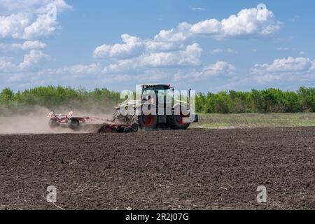 19. Mai 2023, Region Kherson, Ukraine: Das vor kurzem entminte Feld wird nach der Befreiung von der russischen Invasion für die Anpflanzung auf dem Bauernhof Pershe Travnia im Dorf Velyka Oleksandrivka in der Region Kherson gepflügt. Der Betrieb erzeugte Getreide (Weizen, Gerste, Sonnenblumen), Fleisch (Schweinefleisch) und andere Erzeugnisse; Mit 100 Beschäftigten und mehr als 3.000 Hektar Ackerfläche, mehr als 1200 Schweinen. Der Betrieb wurde vollständig zerstört, die gesamte Ausrüstung, die Ernte von 2021, der Dünger, alle Gebäude einschließlich Getreidelager und Orte, an denen Schweine gehalten und gefüttert wurden. Nach den Bombenanschlägen wurden Schweine entweder lebendig verbrannt, einige in Panik gesprungen Stockfoto