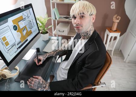 Tätowierter Grafikdesigner, der im Büro am Tisch arbeitet Stockfoto