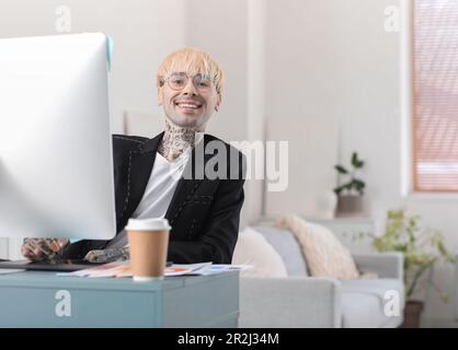 Tätowierter Grafikdesigner, der im Büro am Tisch arbeitet Stockfoto
