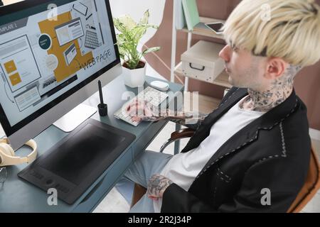 Tätowierter Grafikdesigner, der im Büro am Tisch arbeitet Stockfoto