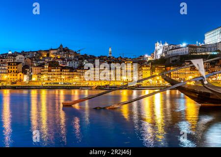 Blick über die traditionellen Rabelo-Boote am Douro-Flussufer in Vila Nova de Gaia bis zur Altstadt von Porto in der Abenddämmerung, Vila Nova de Gaia, Portugal, Euro Stockfoto