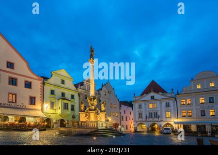 Brunnen und Pestsäule mit traditionellen Häusern mit Giebeln im Hintergrund in der Abenddämmerung, Namesti Svornosti Platz im historischen Zentrum, UNESCO Stockfoto