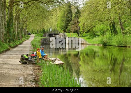 Zwei Personen radeln entlang des Canal du Midi und machen eine Pause an der Schleuse, in der Nähe von Castelnaudary, Canal du Midi, UNESCO-Weltkulturerbe Canal du Midi, Okzitan Stockfoto