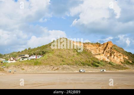 Bayleys Beach Neuseeland - März 6 2011; Ferienhäuser und Fahrzeuge auf orangefarbenen Sanddünen und Strand am Bayleys Beach in Northland Neuseeland Stockfoto