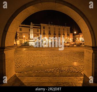 Praktizieren Sie República am Abend mit einem Restaurant im Laternen-Licht, das Sie durch eine Arkade des Rathauses, Tavira, Algarve, Portugal, sehen können Stockfoto