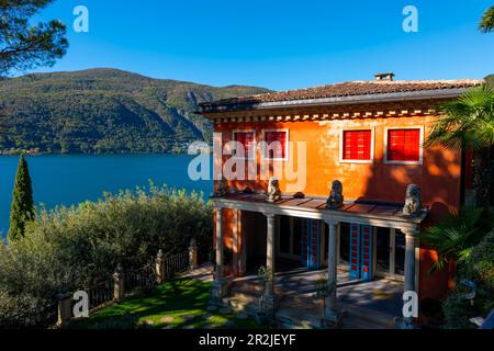 Indisches Haus und Terrasse mit Statue und Luganer See mit Berg und Sonnenlicht im Park Scherrer in Morcote, Tessin, schweiz. Stockfoto