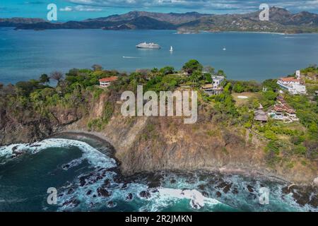 Blick aus der Vogelperspektive auf Villen an der Landzunge mit dem Expeditionsschiff World Voyager (Nicko Cruises) in der Bucht, Playa Flamingo, Guanacaste, Costa Rica, Central Stockfoto