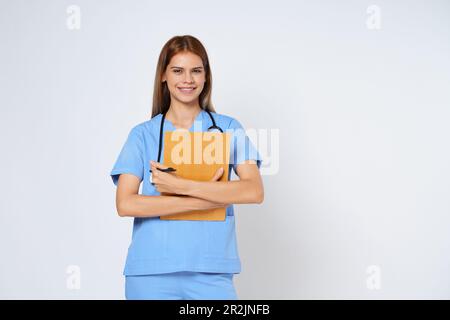 Lächelnde Ärztin mit Klemmbrett und Stethoskop auf weißem Hintergrund isoliert. Stockfoto