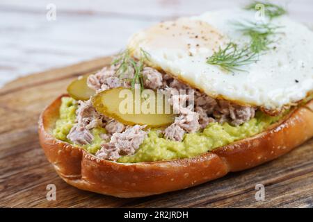 Avocado Toast mit Thunfisch, Spiegeleiern und Dill auf dem Teller. Stockfoto