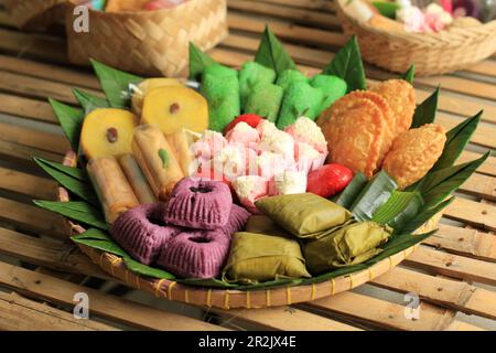 Kue Basah, Jajan Pasar Tampah. Verschiedene traditionelle indonesische Snacks, serviert auf einem gewebten Bambus-Tablett mit Bananenblatt. Stockfoto