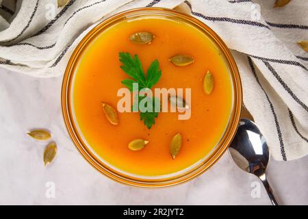 Kürbissuppe mit Kräutern und Kürbiskernen, serviert in einer Schüssel, von oben gesehen. Stockfoto