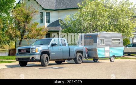 Calgary, Alberta, Kanada. 18. Mai 2023. Ein blauer Truck mit einem alten Campingwagen. Stockfoto