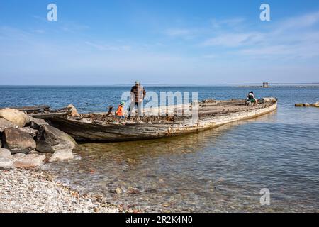 Menschen auf einem alten hölzernen Schiffswrack an einem sonnigen Frühlingstag an der Kalarandküste in Tallinn, Estland Stockfoto