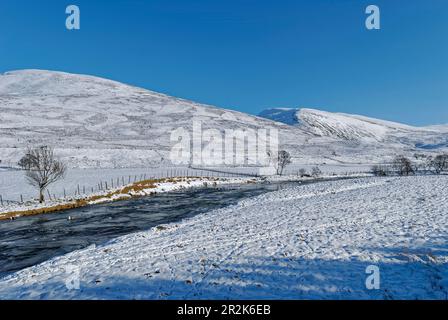 Clunie Wasser fließt das Tal hinunter in Richtung Braemar in Glen Clunie, mit Glenshee in der Ferne an einem Wintertag im Februar. Stockfoto