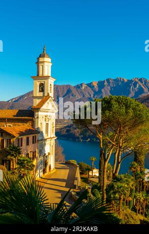 Die Kirche der Heiligen Fedele und Simone und der Luganersee mit dem Berg an einem sonnigen Tag in Vico Morcote, Tessin in der Schweiz. Stockfoto