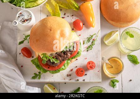 Leckerer gegrillter Hamburger in der Sommerküche. Hausgemachte Burger mit Brötchen und Gemüse. Stockfoto