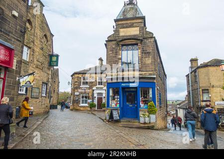 Blick auf die Main Street zu den Kings Arms und dem Pennybank House an der Kreuzung mit West Lane im Dorf Haworth in West Yorkshire, England, Großbritannien Stockfoto