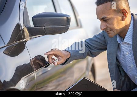 Versicherungsagent inspiziert ein Auto mit einem Kratzer. Stockfoto