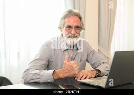 Glücklicher Senior-Mann mit Brille, der sich ein Kameraporträt ansieht Stockfoto