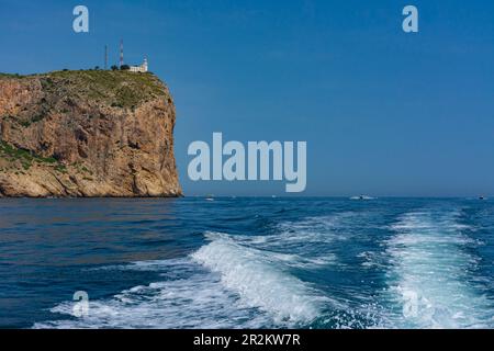 Leuchtturm von Cabo de San Antonio in Jávea im Naturpark Montgo. Kleiner Leuchtturm auf der Klippe. Vom Meer aus an Bord eines Schiffes Stockfoto