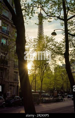 Paris, Frankreich - 24. April 2023: Gemütliche Pariser Straße mit Blick auf den berühmten Eiffelturm bei Sonnenuntergang, Paris, Frankreich Stockfoto