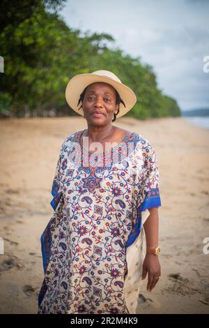 Vertikales Porträt einer erwachsenen Afrikanerin, die während ihrer Ferien am Strand lächelt. Stockfoto