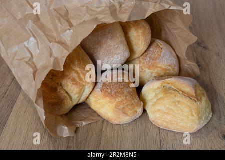 Braune Papiertüte mit italienischem Kunsthandwerksbrot innen auf einem Holztisch Stockfoto