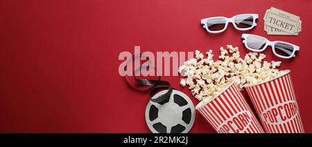 Flache Lagezusammensetzung mit köstlichem Popcorn, Kinokarten und Gläsern auf rotem Hintergrund, Platz für Text. Bannerdesign Stockfoto