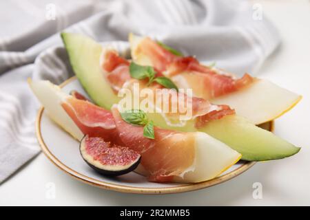 Teller mit leckerer Melone, Jamon und Feigen auf weißem Tisch, Nahaufnahme Stockfoto