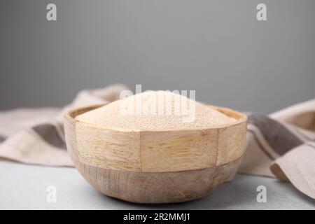 Granulat in einer Holzschüssel auf einem hellgrauen Tisch, Nahaufnahme Stockfoto