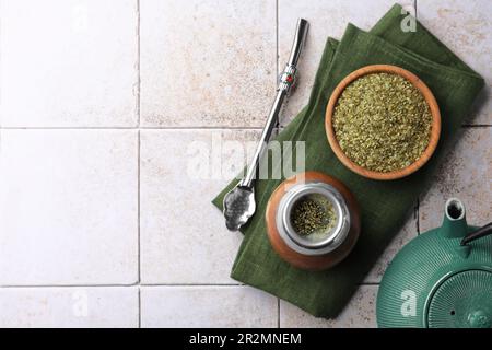 Calabash, Bombilla, Schüssel Teeblätter und Teekanne auf gefliestem Tisch, flach liegend. Platz für Text Stockfoto