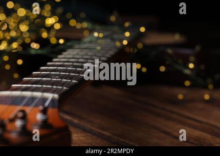 Nahaufnahme der Gitarre auf einem Holztisch vor verschwommenem Licht, Platz für Text Stockfoto